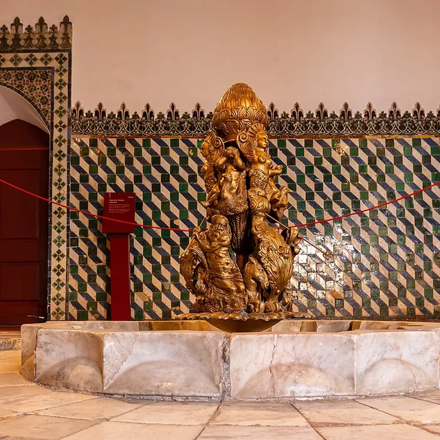 The Mudéjar fountain at the centre of the Sala dos Árabes, ringed by green and blue chequered azulejo tiling.