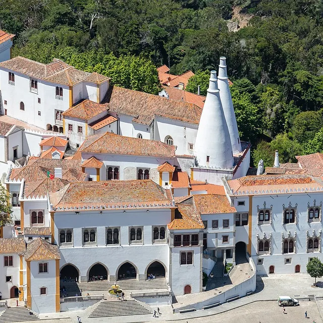 The twin white conical kitchen chimneys of the Palácio Nacional de Sintra rising above the palace's terracotta roofs and the old town.