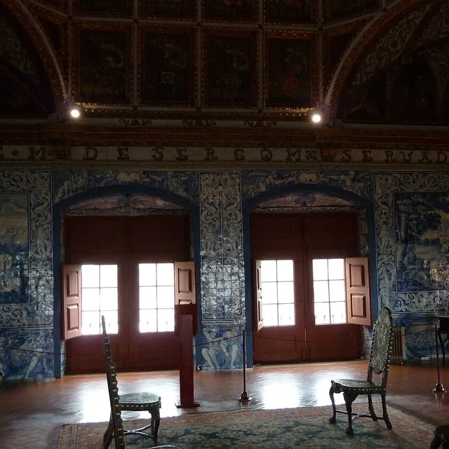 Blue-and-white azulejo panels covering the walls of the Coats of Arms Room in the Sintra National Palace, with an inscribed frieze above the doors.